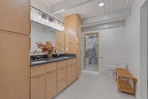 Bathroom with beamed ceiling, a shower stall, double vanity, and light tile patterned flooring