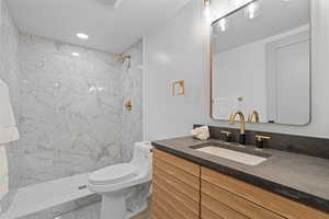 Bathroom featuring vanity, a marble finish shower, and recessed lighting