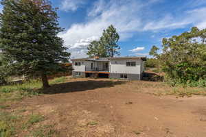 Back of house featuring a chimney, a deck, and stairs