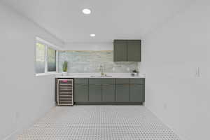 Bar area featuring beverage cooler, decorative backsplash, recessed lighting, and green cabinetry