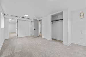 Unfurnished bedroom featuring light carpet and a closet