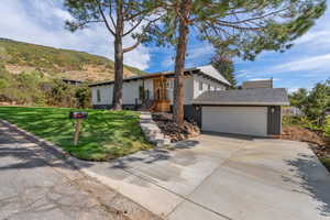 View of front facade featuring concrete driveway, an attached garage, and a front yard