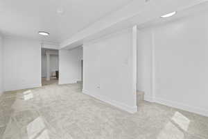 Empty room featuring light colored carpet and stairs