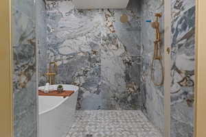 Bathroom with a freestanding tub, a marble finish shower, and tile walls