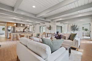 Living area featuring beamed ceiling, light wood finished floors, and recessed lighting