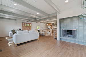 Living area with a fireplace, recessed lighting, light wood-style flooring, and beam ceiling