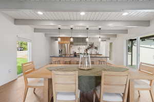 Dining space featuring recessed lighting, bar with sink, light wood-type flooring, and a wooden ceiling with exposed beams