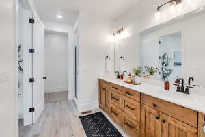 Bathroom featuring double vanity, walk in shower, light wood finished floors