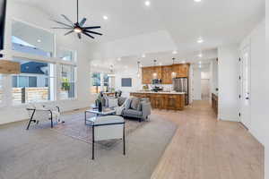 Living room featuring an open floor plan with recessed lighting, ceiling fan, high vaulted ceiling, a chandelier, and light wood finished floors