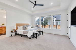 Primary bedroom retreat with tray ceiling, abundant natural light, a ceiling fan, ensuite bath, and recessed lighting