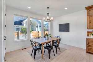 Dining area featuring light wood finished floors, a chandelier, and recessed lighting