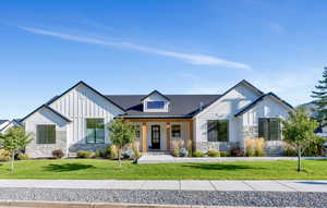 Modern farmhouse with stone,  board and batten siding, and large welcoming front porch