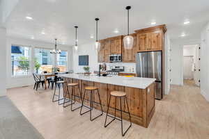 Kitchen featuring stainless steel appliances, a kitchen breakfast bar, hanging light fixtures, and recessed lighting