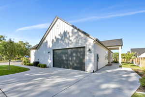 View of property exterior with board and batten siding and concrete driveway