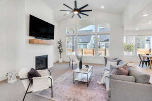 Living room with abundant natural light, a large fireplace, high vaulted ceiling, recessed lighting, and a ceiling fan