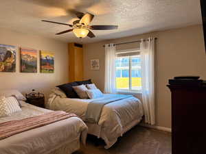 Bedroom featuring a textured ceiling, carpet flooring, and a ceiling fan