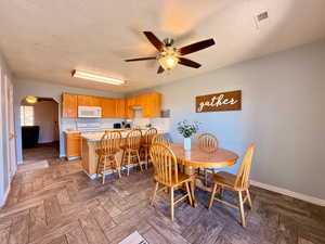 Dining area with a ceiling fan, a textured ceiling, and arched walkways