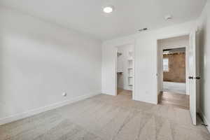 Unfurnished bedroom with light colored carpet and a spacious closet