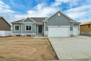 View of front of property with board and batten siding, a garage, and driveway
