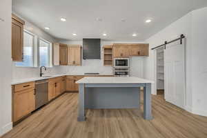 Kitchen with a barn door, light stone counters, decorative backsplash, light wood-type flooring, and open shelves