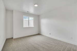 Spare room featuring light carpet and baseboards