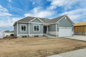 View of front of property with board and batten siding, driveway, roof with shingles, and an attached garage