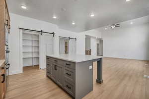 Kitchen with gray cabinets, a center island, light wood-style floors, a kitchen breakfast bar, and open floor plan