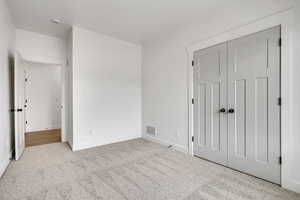 Unfurnished bedroom featuring light carpet and a closet