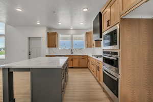 Kitchen featuring light stone countertops, stainless steel appliances, a kitchen island, light wood-style flooring, and recessed lighting