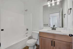 Bathroom featuring vanity, bathing tub / shower combination, and dark wood-type flooring