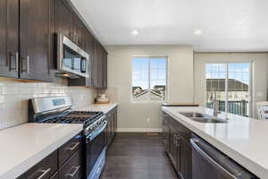 Kitchen featuring stainless steel appliances, healthy amount of natural light, dark wood-style floors, decorative backsplash, and recessed lighting