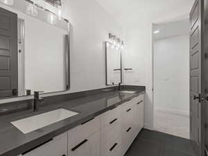 Bathroom with double vanity, dark tile patterned flooring, and recessed lighting