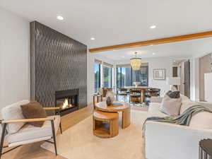 Great room featuring a fireplace, beamed ceiling, recessed lighting, a chandelier, and wood finished floors