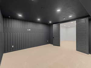 Finished below grade area with light colored carpet, recessed lighting, and a textured ceiling