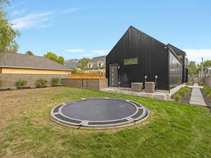 Fenced backyard featuring a trampoline and a patio area