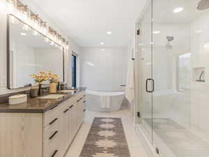 Bathroom with vanity, a freestanding tub, a stall shower, light tile patterned flooring, and recessed lighting