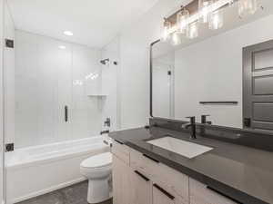 Full bath with bath / shower combo with glass door, vanity, and recessed lighting