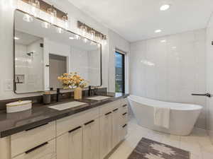 Full bath with a freestanding tub, double vanity, tile walls, light tile patterned flooring, and recessed lighting
