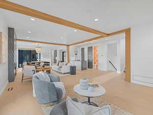 Living room with light wood finished floors, recessed lighting, a chandelier, and beamed ceiling