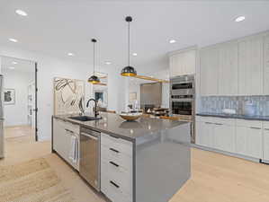 Kitchen with tasteful backsplash, hanging light fixtures, a kitchen island with sink, recessed lighting, and modern cabinets