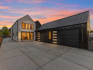 View of rear facade featuring a standing seam roof, a metal roof, and driveway