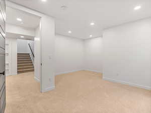 Below grade area with recessed lighting, light carpet, and stairway