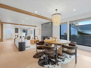 Dining space featuring recessed lighting, light wood-style floors, beamed ceiling, a large fireplace, and a chandelier