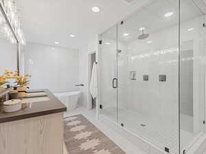 Full bathroom with tile walls, a shower stall, vanity, a soaking tub, and tile patterned floors