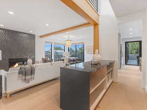 Bar area  featuring light wood-type flooring, a fireplace, recessed lighting, beamed ceiling, and decorative light fixtures