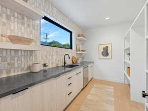 Kitchen with decorative backsplash, dark countertops, light wood-style floors, recessed lighting, and dishwasher