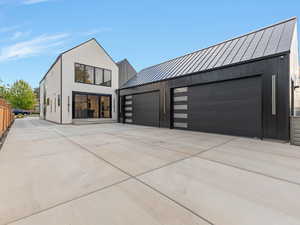 Modern home featuring a standing seam roof, a metal roof, a garage, board and batten siding, and driveway