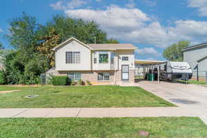 View of front facade with brick siding, concrete driveway, a front yard, and a carport