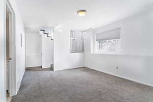 Empty room featuring light colored carpet and stairway