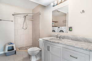Full bathroom with vanity, tile patterned flooring, washing machine and clothes dryer, and a stall shower